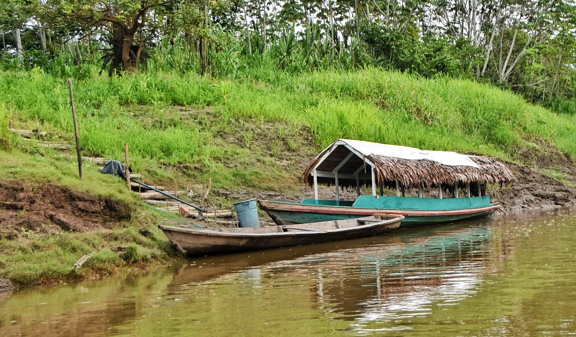 Barca descansando en la orilla del río durante la época seca en la selva de Iquitos, con la vegetación amazónica al fondo