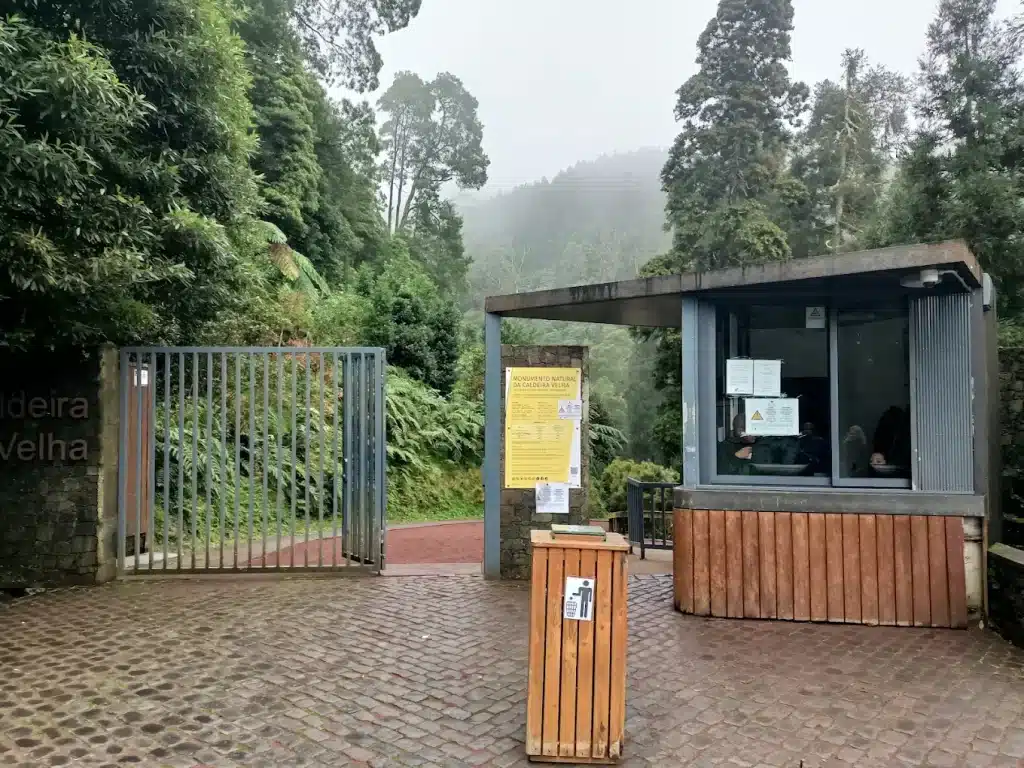 Taquilla de entrada a Caldeira Velha, una pequeña caseta de madera rodeada de vegetación, donde los visitantes enseñan el acceso antes de iniciar la visita.