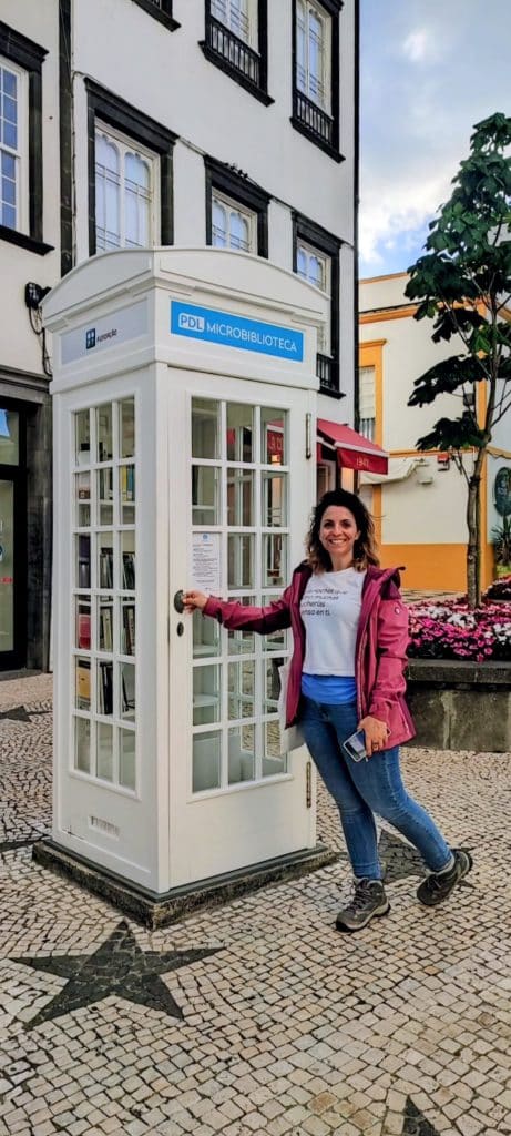 Montse dentro de la mini biblioteca de Ponta Delgada, instalada en una antigua cabina telefónica blanca