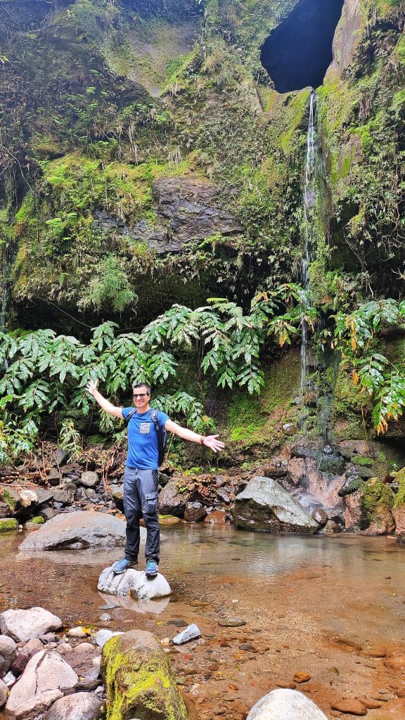 Domi con los brazos abiertos sobre una roca en medio de una cascada en la PRC37 SMI Rota da Água – Janela do Inferno.