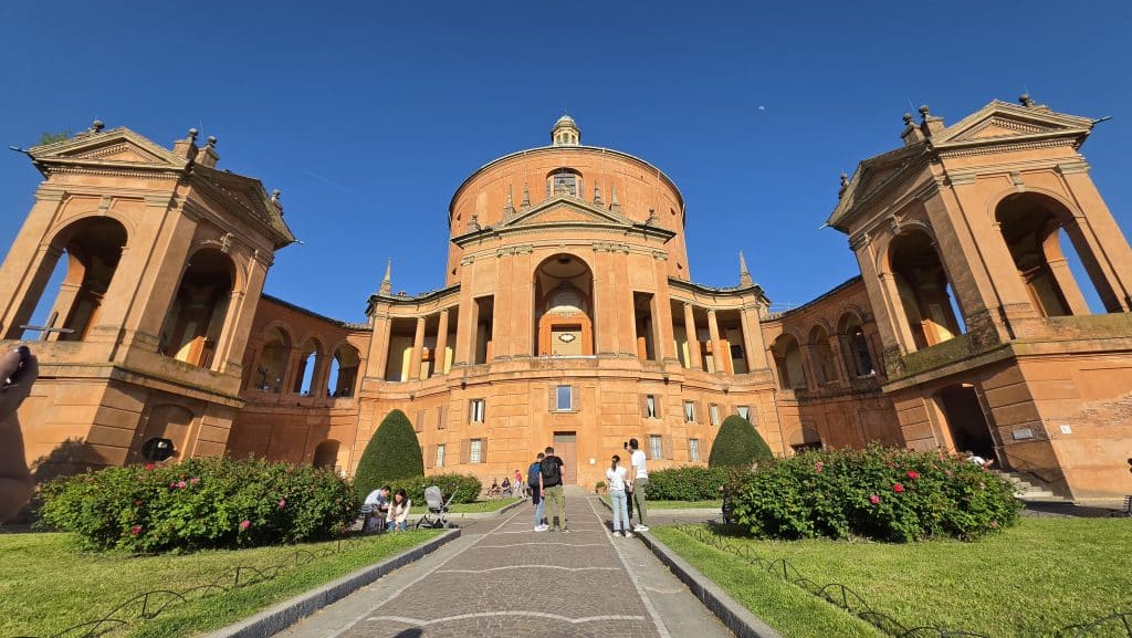 Basílica barroca de San Luca en lo alto del Colle della Guardia, conectada con Bolonia por un largo pórtico y accesible andando, en autobús o taxi.