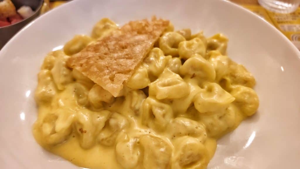 Plato de cappelletti rellenos servidos con salsa de Parmigiano Reggiano, especialidad tradicional de la cocina de Emilia‑Romaña.