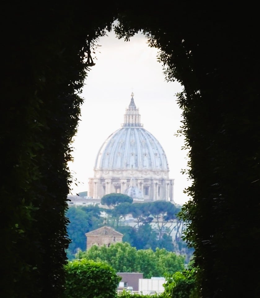 Cúpula de la Basílica de San Pedro vista a través de la cerradura de la Villa Magistral de la Orden de Malta, con el jardín enmarcando la perspectiva